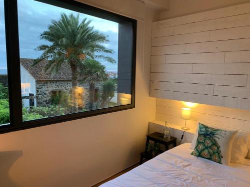 a bedroom with a large window with a palm tree at 2Azores With Comfort and Style in Ponta Delgada