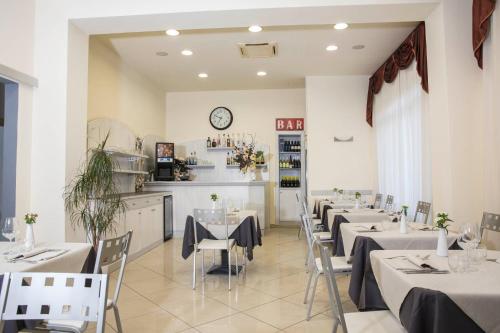a restaurant with tables and chairs and a clock on the wall at Hotel Playa in Viareggio