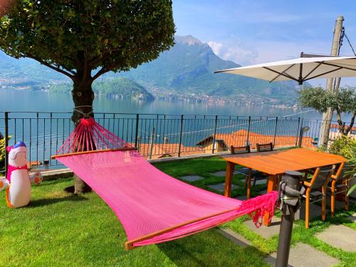 a hammock sitting next to a table and a lake at Residence Molinari Lake Como in Lezzeno