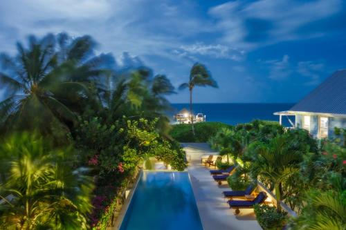 a resort with a swimming pool and palm trees at Weezie's Ocean Front Hotel and Garden Cottages in Caye Caulker
