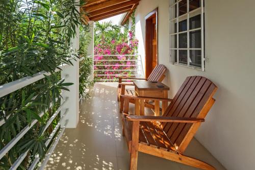 two chairs on the porch of a house with flowers at Weezie's Ocean Front Hotel and Garden Cottages in Caye Caulker