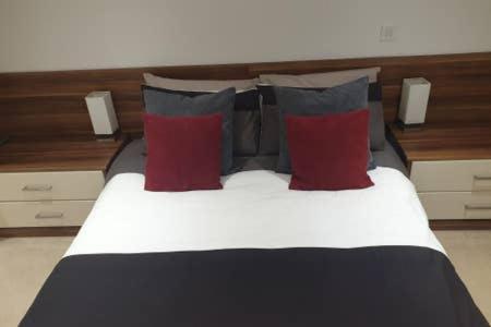 łóżko z czerwonymi i niebieskimi poduszkami w pokoju w obiekcie Hullidays - The Sawmill Suite w mieście Hull