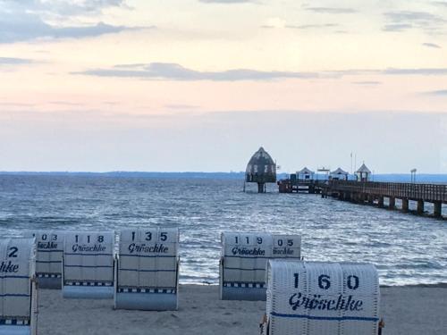 a beach with chairs and a pier and the ocean at Ostseeperle in Grömitz