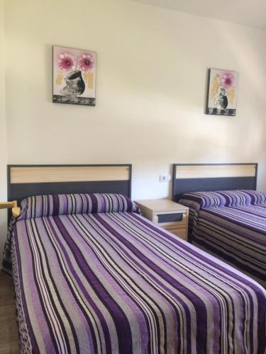 two beds in a room with purple striped sheets at CHALET MUY CERCA DE LA PLAYA CON PISCINA PRIVADA in Orihuela Costa