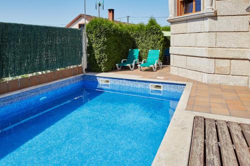 - une piscine avec deux chaises bleues à côté d'une clôture dans l'établissement Gándara Chalet, à Salvatierra de Miño