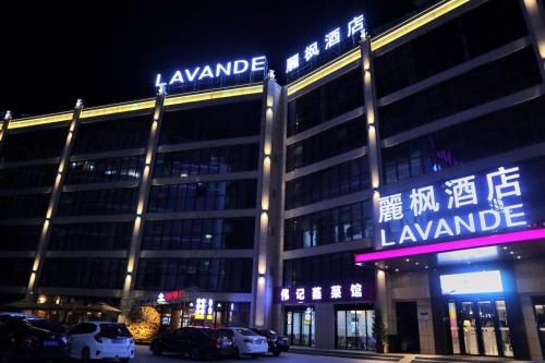 a lit up building with cars parked in front of it at Lavande Hotel Huizhou High-speed Railway South Station Wanlian Square in Huizhou