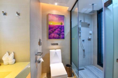 a bathroom with a shower and a painting on the wall at Lavande Hotel Huizhou High-speed Railway South Station Wanlian Square in Huizhou