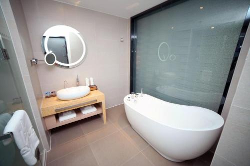 a bathroom with a tub and a sink and a mirror at Lavande Hotel Taian Dongyue Street Daimiao in Tai'an