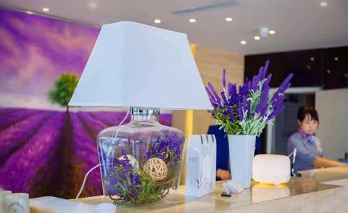 a lamp with a vase of flowers on a table at Lavande Hotel Yinchuan Railway Station Wanda in Yinchuan