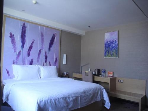 a bedroom with a large white bed with a painting on the wall at Lavande Hotel Yinchuan Railway Station Wanda in Yinchuan