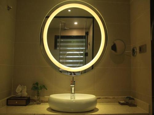 a bathroom with a sink and a round mirror at Lavande Hotel Yinchuan Railway Station Wanda in Yinchuan