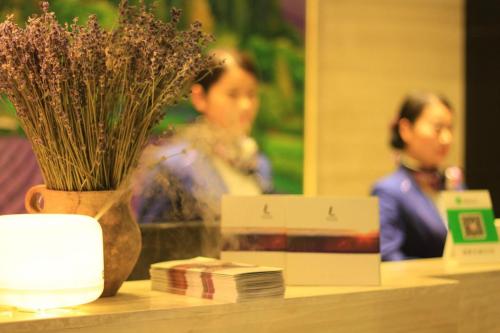 a table with a vase of flowers and a mirror at Lavande Hotel Tianshui Gangu Jicheng Square in Tianshui