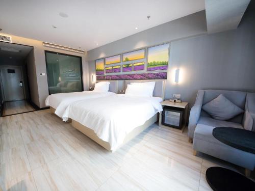 a bedroom with a large white bed and a couch at Lavande Hotel Urumqi High-speed Railway wanda plaza in Ürümqi