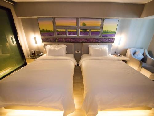 two beds in a room with two windows at Lavande Hotel Urumqi High-speed Railway wanda plaza in Ürümqi