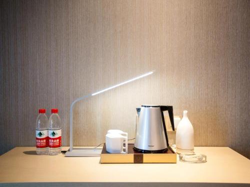 a table with a lamp and a coffee maker on it at Lavande Hotel Urumqi High-speed Railway wanda plaza in Ürümqi