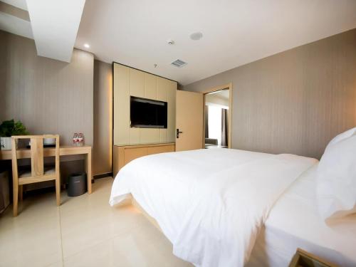 a bedroom with a bed and a desk and a television at Lavande Hotel Urumqi High-speed Railway wanda plaza in Ürümqi