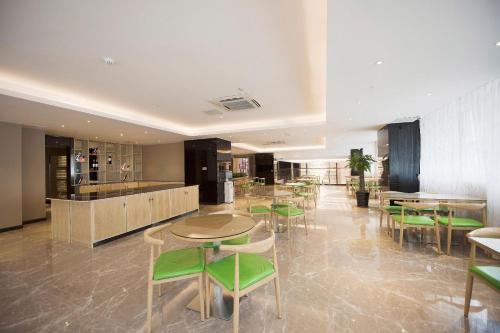 um restaurante com mesas e cadeiras verdes numa sala em Lavande Hotel Zhongshan Shaxi em Changzhou