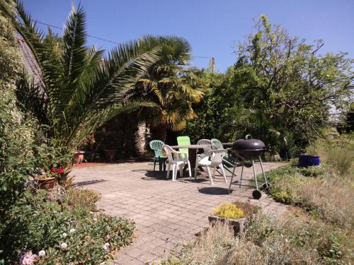 a patio with chairs and a grill in a garden at L'Ecurie in Saint-Ségal
