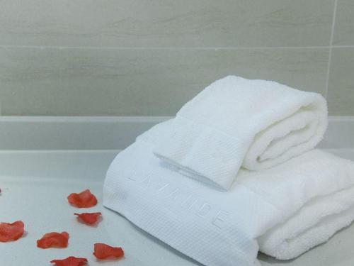 un asciugamano bianco e alcuni fiori rossi su una vasca da bagno di Lavande Hotel Zhanjiang Xuwen Tianrunhui a Xuwen