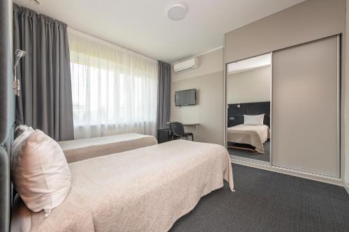 a hotel room with two beds and a mirror at Jūratės B&B Namai in Karmėlava