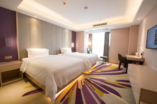 a hotel room with two beds and a desk at Lavande Hotel Luzhou BBQ new World in Luzhou