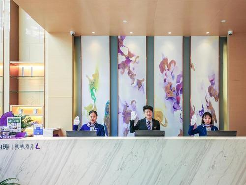 a group of three men sitting at a table with their laptops at Lavande Hotel Zhengzhou Longhai West Road Subway Station in Zhengzhou