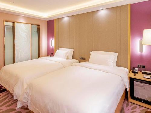 two beds in a hotel room with white sheets at Lavande Hotel Zhengzhou Longhai West Road Subway Station in Zhengzhou