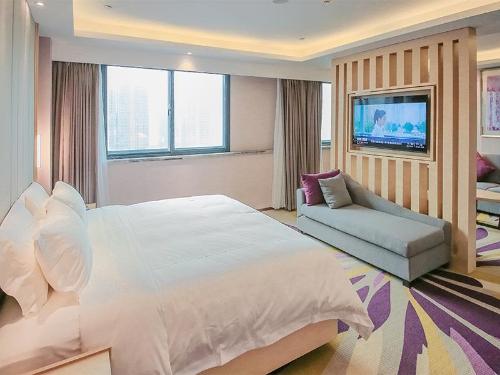 um quarto com uma grande cama branca e um sofá em Lavande Hotel Zhengzhou Longhai West Road Subway Station em Zhengzhou