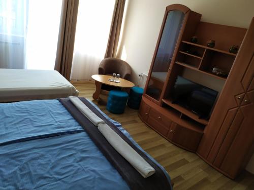 a bedroom with a bed and a dresser and a tv at Szilvia Panzió Gyomaendrőd in Gyomaendrőd