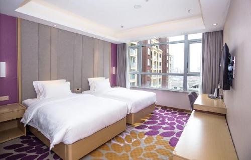 a hotel room with two beds and a flat screen tv at Lavande Hotel Neijiang High-speed Railway Station Peace Plaza in Neijiang