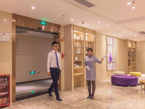 two men and a woman standing in a lobby at Lavande Hotel Chongqing Jiangbei International Airport Center in Yubei