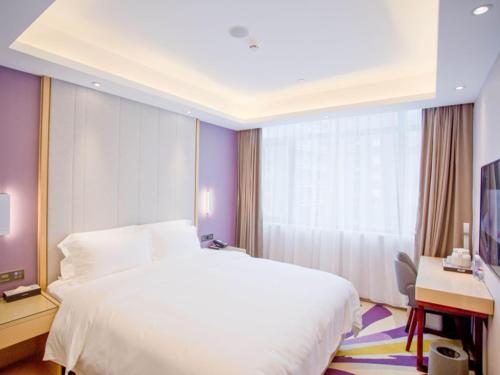 a bedroom with a large white bed and a desk at Lavande Hotel Dongguan Houjie Convention Cente Shanmei subway station in Dongguan