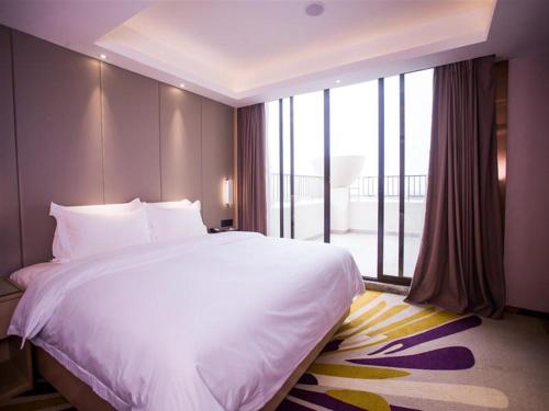 um quarto com uma cama grande e uma janela grande em Lavande Hotel Dongguan Houjie Convention Cente Shanmei subway station em Dongguan