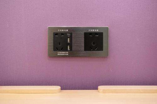 a lightswitch on a purple wall next to a table at Lavande Hotel Heyuan Longchuan in Longchuan