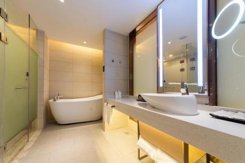 a bathroom with a tub and two sinks and a bath tub at Lavande Hotel Heyuan Longchuan in Longchuan