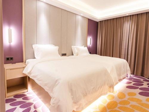 a large white bed in a bedroom with purple walls at Lavande Hotel Heyuan Longchuan in Longchuan