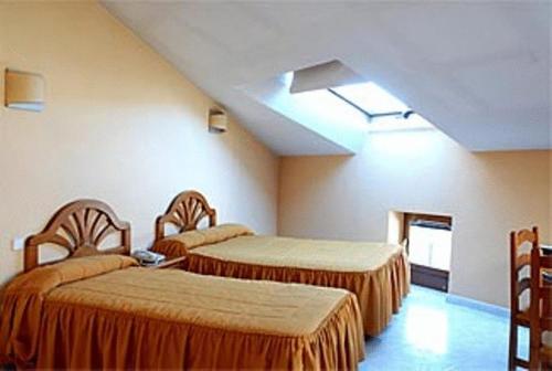 a hotel room with two beds and a skylight at Hotel Laberinto in Sigüenza