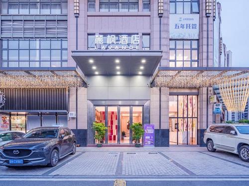 dwa samochody zaparkowane na parkingu przed budynkiem w obiekcie Lavande Hotel Zhaoqing Qixingyan Scenic Spot Yihua International Square w mieście Zhaoqing