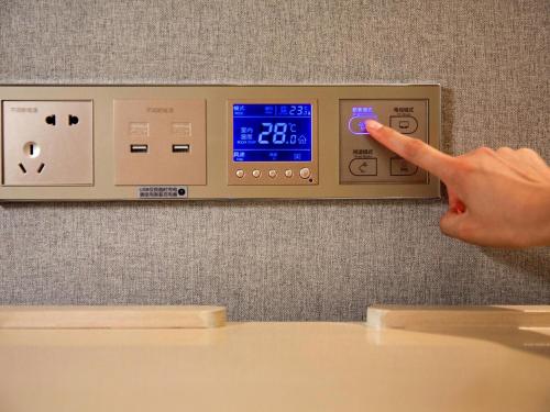 a person pointing to a lightswitch on a wall at Lavande Hotel Yibin University City Exhibition Center in Yibin