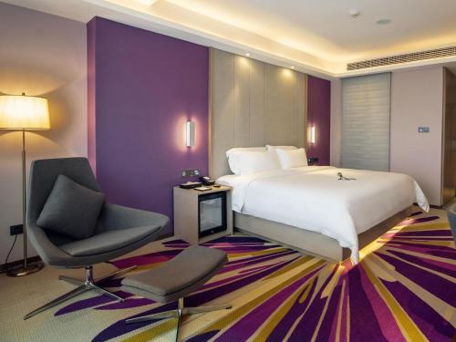 a hotel room with a large bed and a chair at Lavande Hotel Yibin University City Exhibition Center in Yibin