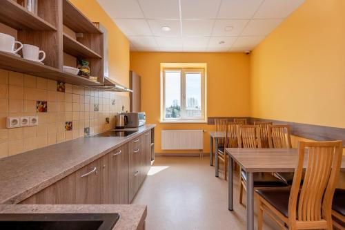 a kitchen with yellow walls and wooden tables and chairs at Air Kaunas in Karmėlava