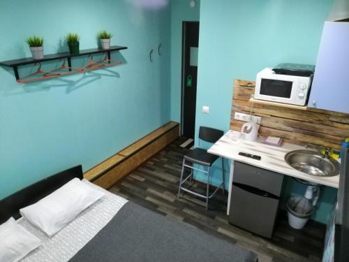 a small room with a bed and a sink and a microwave at Apartments Vavilon 4 in Yekaterinburg