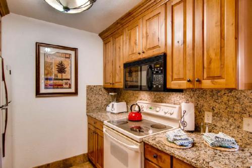 La cuisine est équipée de placards en bois et d'une cuisinière blanche. dans l'établissement Eagle Point Resort, à Vail