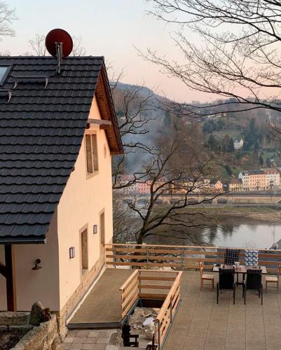 a building with a table and chairs next to a lake at Luxusboofe - Ferienhaus am Lilienstein in Königstein an der Elbe