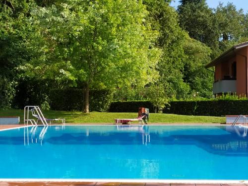 uma grande piscina azul com uma árvore ao fundo em Rosalinde House em Colà di Lazise