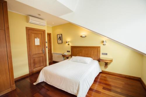 a bedroom with a white bed and a staircase at Hotel El Sella in Cangas de Onís