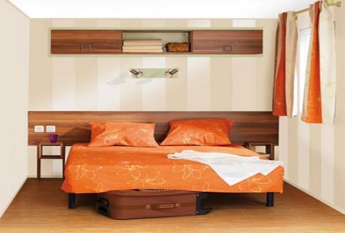 a bedroom with a bed with an orange bedspread and an orange headboard at Résidence Santa in Ghisonaccia