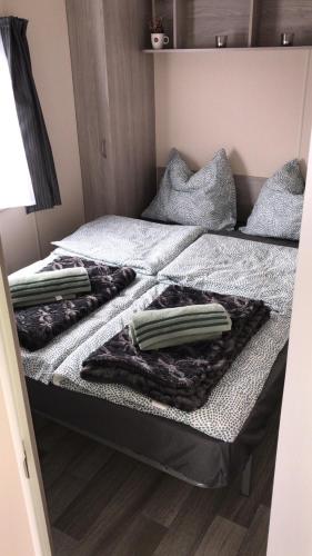 two beds with blankets and pillows on them in a room at Luxe Chalet op camping Duindoorn, IJmuiden aan Zee, in de buurt van F1 circuit Zandvoort en Bloemendaal op loopafstand strand in IJmuiden
