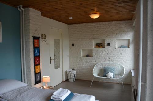 a bedroom with a bed and a white brick wall at Vakantiehuis 't Geultje in Schin op Geul