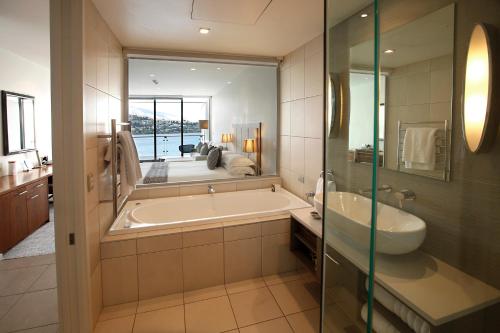 a bathroom with a tub and a sink and a mirror at The Rees Hotel & Luxury Apartments in Queenstown